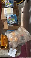 Assortment of small machinery parts, some in original packaging, with boxes and bags on table