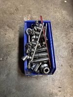 Photo showing a blue storage bin filled with various chrome sockets and ratchet wrenches.