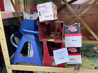 Blue and red metal vehicle stands next to stacked filter boxes and sawhorse brackets showing wear and use