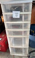 Front view of six-drawer plastic storage bin showing contents of drawers in shaded transparent plastic.