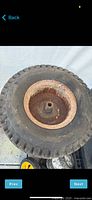 Riding lawn mower tire mounted on rusted metal wheel showing general condition and tread.
