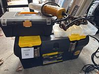 Stanley toolbox with two small plastic storage containers stacked on top, also showing the chain coiled on the toolbox