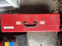 Top view of the closed red metal toolbox showing black handle and two latches.
