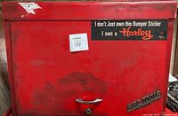 Front view of red Mac Tools chest showing Harley bumper sticker, scratches, paint wear, handle, lock, and Mac Tools logo.