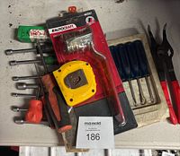 Top view of various hand tools arranged including screwdrivers, tape measure, tube bender, snap ring pliers, and nut driver set