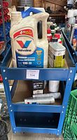 Top view of blue metal utility cart loaded with assorted chemical containers on top shelf