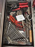 Assorted hand tools including locking pliers, slip joint pliers, wire cutters, combination wrenches, and various files and scrapers in a drawer.