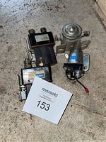 Overview photo showing three vehicle electrical parts: Cole Hersee glow plug relay, solenoid, and Haldex relay on floor