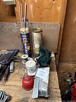 Photo showing welding electrodes in Pringles container, welding flux, welding wire coil, solder rolls, and green welding goggles.