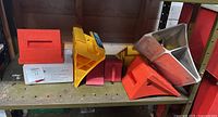 Various different wheel chocks in orange, yellow and silver placed on a shelf
