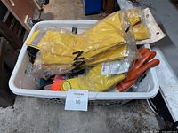 Plastic basket containing various types of work gloves including large yellow rubber gloves and tan gloves