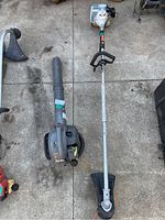 Blower and straight-shaft trimmer side by side on concrete driveway