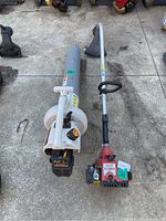 Photo of Ryobi blower vacuum and Homelite string trimmer side by side on concrete ground.