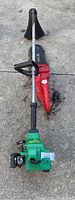 FeatherLite weed eater showing green engine base and long metal shaft with handle on concrete surface.