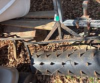 Angle showing spike aerator roller with metal triangular frame and hitch components