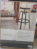 Box of Threshold Lewiston Adjustable Stool with product details and image showing metal stool with round wooden seat and hammered bronze finish, assembly required.