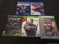 Top view showing all five sealed video games for Xbox 360, Xbox One, and PS4, arranged on a carpeted surface.