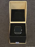 AI smartwatch displayed inside beige and black retail box with foam padding.