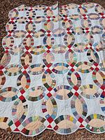 Full view of vintage double wedding ring quilt laid flat showing overall pattern and scalloped edge.