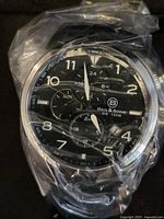 Close-up of the Ben & Sons watch face showing black dial, white numerals, three subdials, date window, and plastic wrap indicating new condition.