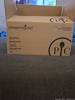 Closed cardboard box with Pampered Chef branding and product details