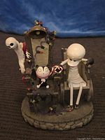 Nightmare Before Christmas themed figurine set including seated skeleton figure, ghostly figure, and small candy cane character with base and accessories