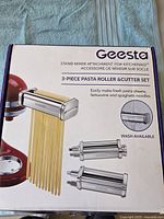 Box showing Geesta 3-piece pasta roller and cutter set compatible with KitchenAid stand mixers.