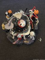 Front view of the large Nightmare Before Christmas snow globe, showing the characters Jack Skellington in Santa outfit inside the globe, and detailed figures of Zero, Sally, Lock, Shock, Barrel, and others around the base.