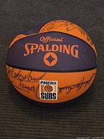 Front and top view of the signed Spalding basketball showing Phoenix Suns logo and multiple signatures in black ink.