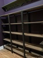 Front angle view showing three shelving units side by side against purple wall on hardwood floor