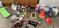 Photo shows battery jumpstart packs, assorted auto fluids, orange cones and tools on the floor.