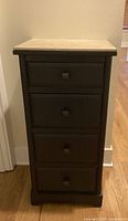 Front view of the narrow black cabinet showing all four drawers and tile top.