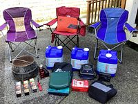 Wide view of entire camping lot items outdoors including chairs and water containers
