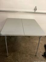 Front angled view of the Coleman folding table showing the gray plastic surface and metal legs.