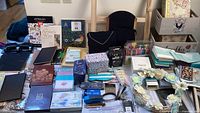 Wide view of assortment of journals, decorative boxes, papers, and crafting tools on table.
