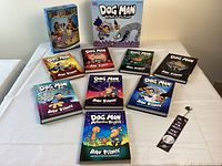 Full display of ten books and two board games with keychain and bookmark on a white table.