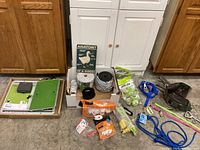 Overview of lot items including electric fence supplies, goat collars, booklet, and Omlet auto door parts outside box