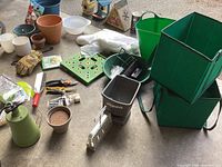 Overview of gardening lot arranged on concrete floor showing seeders, feeders, pots, tools, and accessories.
