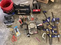 Full overview of all tools, clamps, wrenches, safety glasses, and tool bags laid on concrete floor.