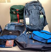 Shows all items: Osprey backpack, North Face daypack, REI duffel and packing organizers