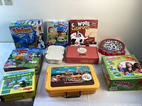 Overview of all nine games in their boxes including Hungry Hungry Hippos, fishing game, Elfun, and others arranged on a white surface.