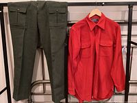 Photo showing dark olive green wool pants by Filson with multiple buttoned pockets on the front and side.