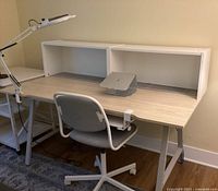 Full view of IKEA Utespelare desk with attached two storage shelves, laptop stand, clamp-on lamp, and office chair.