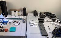Full lot overview showing various Amazon Echo speakers, surge protectors, smart plugs, cables, and other office tech accessories on white tablecloth.