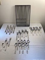 Overview of all flatware pieces including knives, forks, tablespoons, teaspoons, and flatware organizer arranged on white cloth.