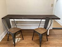 Photo of large rolling table with butcher block top and two industrial metal chairs with wood seats, showing size and condition.