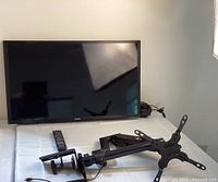 Samsung 32-inch TV with Wali wall mount and various remotes and streaming devices arranged on table