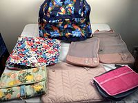 Overview of all items including parrot print duffel bag and smaller floral and mesh travel organizing pouches displayed on a surface