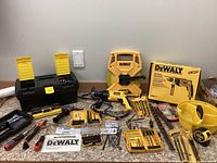 Dewalt hammer drill, measuring tapes, bit sets and assorted hand tools arranged on table