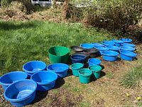 Overview of the full lot arranged on grass showing all tubs and buckets in blue, black, and green colors